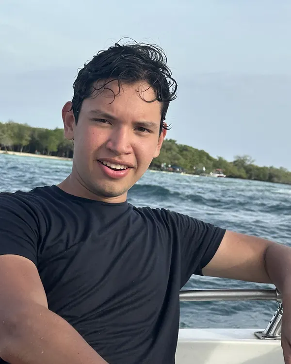 Jostin Marquinas, fundador de MaClo, sonriendo en un bote frente a la costa
